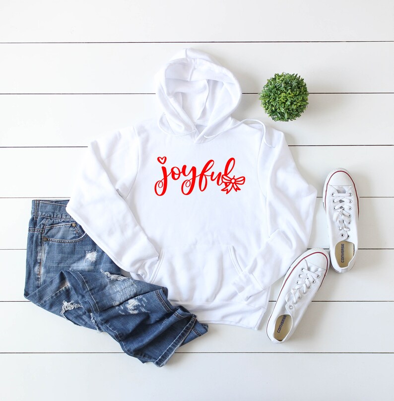 May include: White hoodie with a red graphic that says "joyful" with a small heart and a bow.