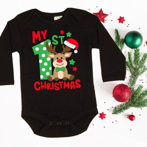 Op de afbeelding: Zwarte romper met lange mouwen met een groene en rode rendierprint en de tekst "My 1st Christmas".