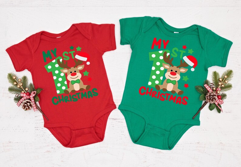 Op de afbeelding: Twee rood-groene korte mouwen onesies met de tekst "My 1st Christmas" en een cartoon rendier met een kerstmanmuts.