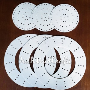 May include: Set of six white plastic round wreath forms with holes for crafting. The forms are in different sizes, with the smaller ones nested inside the larger ones.