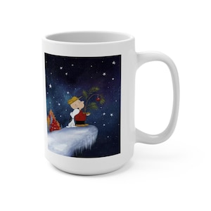 May include: White ceramic mug featuring a colorful illustration of a cartoon character holding a small Christmas tree with a red ornament. The background depicts a starry night sky. The mug has a large handle.