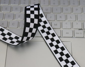 May include: Black and white checkered elastic ribbon on a white laptop keyboard.
