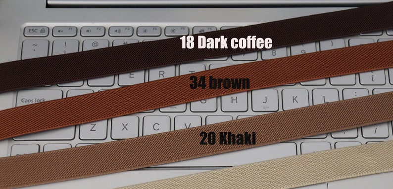 May include: Four different colored elastic bands laid out on a laptop keyboard. The bands are labeled with numbers and colors: 18 Dark coffee, 34 brown, 20 Khaki.