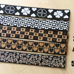 May include: Five different black and white elastic bands with various heart patterns. The bands are numbered 1 through 5.