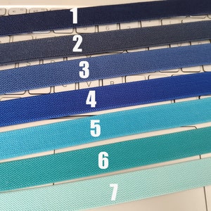 May include: Seven different colors of elastic bands, ranging from dark blue to light blue. The elastic bands are numbered 1 through 7.