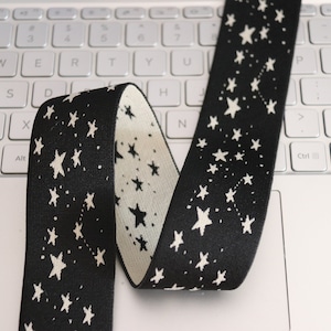 Puede incluir: Banda elástica negra con un patrón de estrellas blancas. La banda es reversible, con un fondo blanco y estrellas negras en el otro lado.