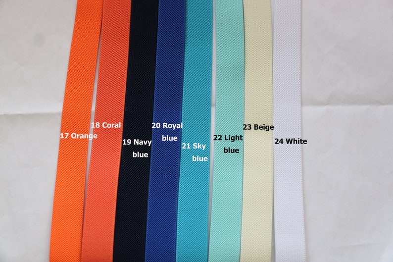 May include: A close-up of eight different coloured fabric straps. The straps are labelled with numbers and colours, including orange, coral, navy blue, royal blue, sky blue, light blue, beige, and white.