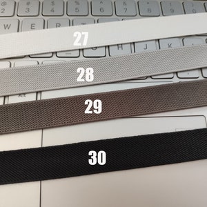 May include: Four different types of elastic bands, labeled 27, 28, 29, and 30, are laid out on a white keyboard.