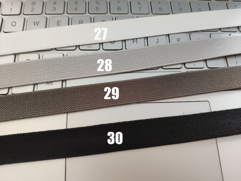 May include: Four different types of elastic bands, labeled 27, 28, 29, and 30, are laid out on a white keyboard.