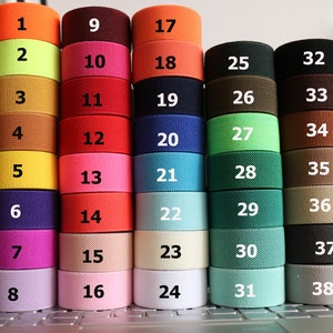 May include: A collection of 38 different coloured elastic bands, each with a number from 1 to 38. The bands are arranged in rows of four, with the numbers increasing from left to right and top to bottom. The colours include orange, yellow, red, green, blue, brown, and grey.