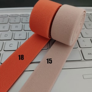 May include: Two rolls of elastic fabric, one orange and one beige, with the numbers "18" and "15" printed on them.