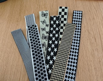 May include: A collection of patterned ribbons in various designs, including stripes, polka dots, butterflies, stars, houndstooth, checkered, and diamond patterns. The ribbons are in black, white, and beige colors.