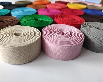 May include: A variety of colors of elastic trim, including beige, pink, green, red, brown, and gray. The trim is rolled up and arranged in a semi-circle.