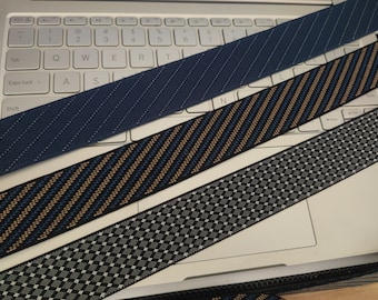 May include: Three different types of elastic trim with various patterns. The trim is blue with white stripes, black with gold and blue stripes, and black with a gray and white checkered pattern.