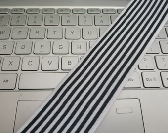 May include: Black and white striped elastic band. The band is lying on a white laptop keyboard.