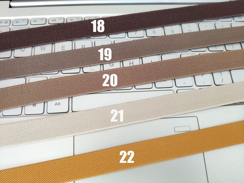 May include: Five different colors of elastic webbing, labeled 18, 19, 20, 21, and 22. The webbing is laid out on a white laptop keyboard.