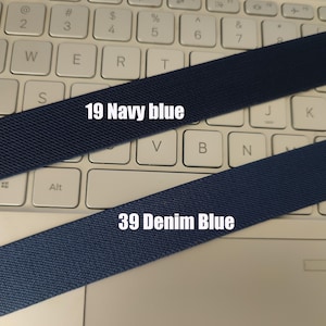 May include: Two fabric straps, one navy blue and one denim blue, are laid out on a white keyboard. The navy blue strap has the text "19 Navy blue" printed on it. The denim blue strap has the text "39 Denim Blue" printed on it.