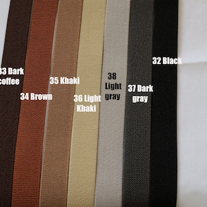 May include: A close-up of eight different coloured elastic bands. The colours are dark coffee, brown, khaki, light khaki, light grey, dark grey, and black. The elastic bands are all the same width and have a textured surface.