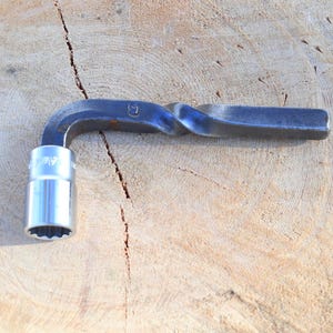 Peut inclure: Une cl&eacute; m&eacute;tallique avec une douille. La cl&eacute; a une poign&eacute;e torsad&eacute;e et une t&ecirc;te de douille argent&eacute;e. L'outil est con&ccedil;u pour serrer ou desserrer les &eacute;crous et les boulons. La cl&eacute; est pos&eacute;e sur une surface en bois.