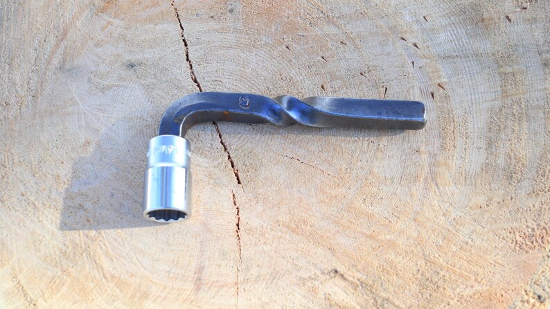 Peut inclure: Une cl&eacute; m&eacute;tallique avec une douille. La cl&eacute; a une poign&eacute;e torsad&eacute;e et une t&ecirc;te de douille argent&eacute;e. L'outil est con&ccedil;u pour serrer ou desserrer les &eacute;crous et les boulons. La cl&eacute; est pos&eacute;e sur une surface en bois.