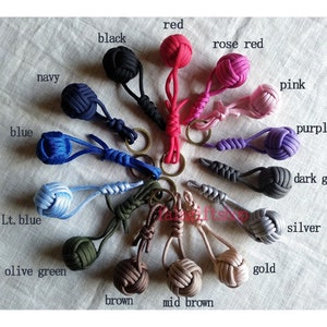 Peut inclure: Une collection de 16 porte-clés noués de couleurs variées, dont rouge, noir, marine, bleu, bleu clair, vert olive, marron, marron moyen, rose rouge, rose, violet, gris foncé, argent et or.