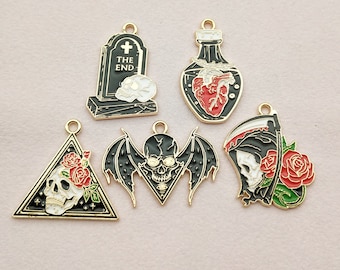 May include: A collection of black and gold enamel charms with gothic and Halloween themes. Designs include a tombstone with "THE END" text, a skull, a bat, a heart in a bottle, and a Grim Reaper with a rose.