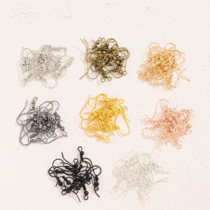 May include: A collection of metal earring hooks arranged in eight distinct piles. The hooks are available in various finishes, including silver, antique bronze, gold, gunmetal, bright yellow gold, rose gold, matte black, and polished white silver.