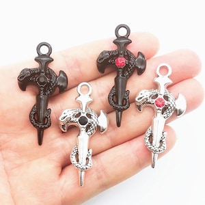 May include: Four metal charms shaped like daggers wrapped in snakes, each featuring a circular loop at the top. Two charms are black with one featuring a red centre stone, and two are silver with one featuring a red centre stone and one black.