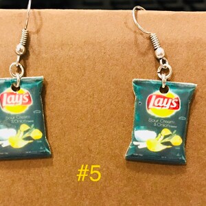 May include: A pair of silver dangle earrings with a miniature Lay's Sour Cream & Onion chip bag charm. The bag is green and blue with the Lay's logo and text.