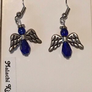 May include: A pair of silver angel wing earrings with blue crystal accents. The earrings are on a white card with the text "Fashion Jewelry" and "Malachi Kitty Bijoux".