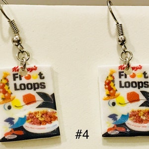 May include: A pair of silver earrings with a white rectangular charm featuring a cartoon bird and the text "Kellogg's Froot Loops".