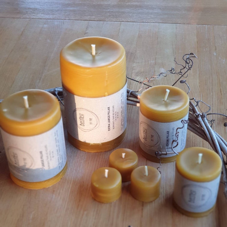 Pu&ograve; includere: Assortimento di sei candele di cera d'api di diverse dimensioni. Le candele sono tutte di colore giallo chiaro e hanno un aspetto naturale e rustico. Le etichette sulle candele recitano "BeezNest by the" e "Extra Large Pillar" e "Medium Pillar".