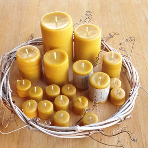 Pu&ograve; includere: Una collezione di 14 candele di cera d'api gialle di diverse dimensioni, disposte su una ghirlanda intrecciata. Le candele sono tutte naturali e non profumate.