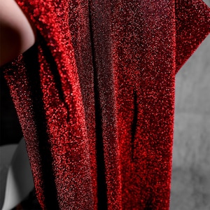 Peut inclure: Tissu rouge scintillant avec une surface texturée et scintillante.
