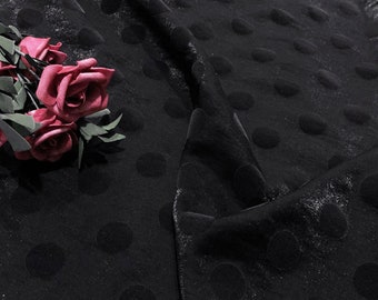 May include: Black fabric with a textured polka dot pattern. The fabric is soft and has a slight sheen.
