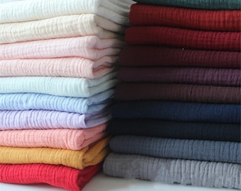 Puede incluir: Un montón de muestras de tela en varios colores, incluyendo blanco, rosa, azul, amarillo, rojo y verde. La tela tiene un aspecto texturizado y arrugado.