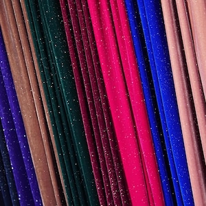 May include: A close-up of a variety of fabric swatches in different colours, including purple, brown, green, red, pink, and blue. The fabric has a sparkly, glittery texture.