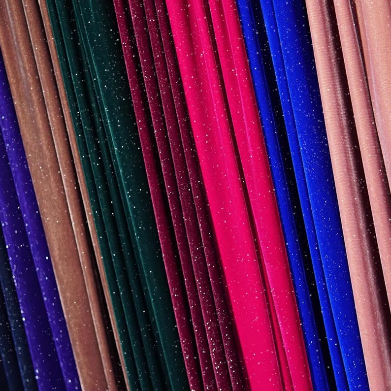 May include: A close-up of a variety of fabric swatches in different colours, including purple, brown, green, red, pink, and blue. The fabric has a sparkly, glittery texture.
