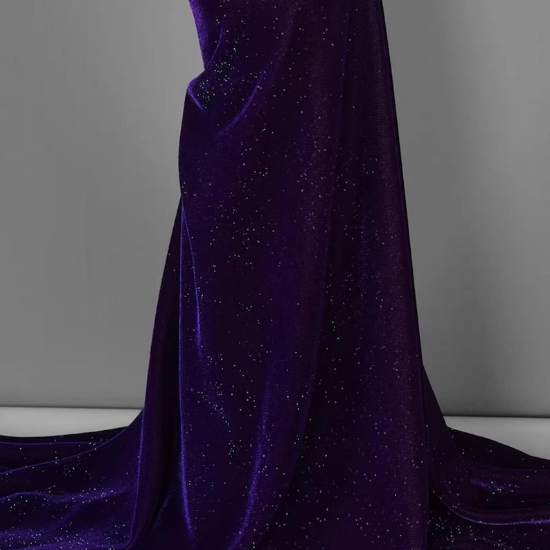 May include: Purple velvet fabric with a sparkly finish. The fabric has a subtle sheen and a soft texture.