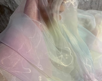 May include: A sheer rainbow ombre fabric with a delicate white pattern. The fabric is soft and flowing, making it perfect for crafting and DIY projects.