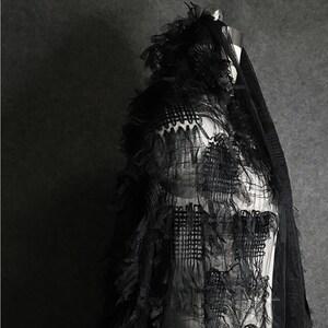 May include: Black sheer fabric with a layered, ruffled design. The fabric has a delicate, almost feather-like texture.