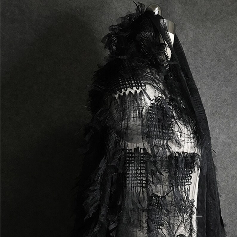 May include: Black sheer fabric with a layered, ruffled design. The fabric has a delicate, almost feather-like texture.