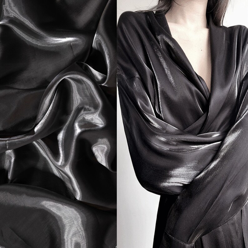 May include: A black satin fabric with a smooth, shiny texture. The fabric is draped and folded, creating a luxurious and elegant look.