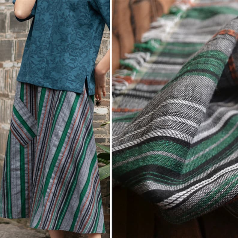 May include: A gray and green striped skirt with a diagonal pattern. The skirt has a large patch pocket on the left side. The fabric is woven with a subtle texture.