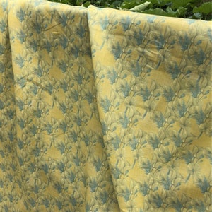 May include: Yellow fabric with a blue floral pattern. The fabric is folded in half and the pattern is visible on both sides.