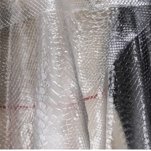 May include: Close-up of a clear, textured plastic sheet with a crocodile skin pattern. The sheet is translucent and has a slight sheen.
