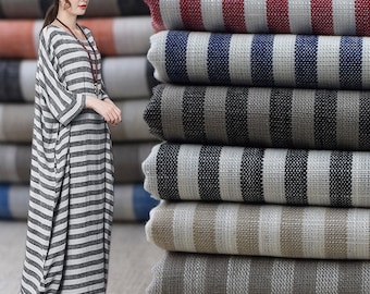 Könnte beinhalten: Ein Stapel gestreiften Stoffes in verschiedenen Farben, darunter Rot, Blau, Schwarz und Beige. Der Stoff ist mit einer subtilen Textur gewebt und hat ein leicht raues Gefühl.