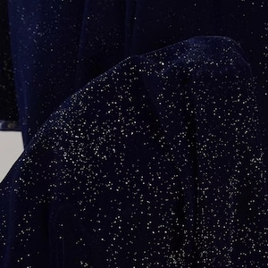 May include: A dark blue fabric with a subtle sparkle of silver glitter. The fabric has a soft, velvety texture.