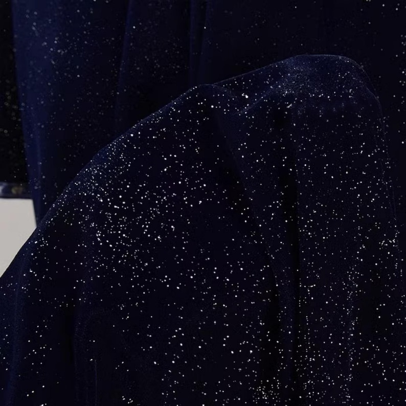 May include: A dark blue fabric with a subtle sparkle of silver glitter. The fabric has a soft, velvety texture.