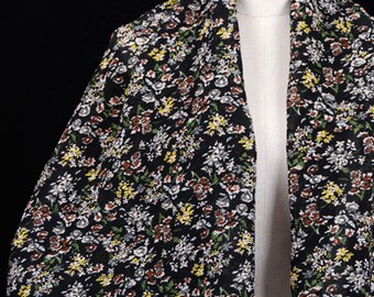 May include: A black scarf with a small floral print in shades of white, yellow, green, and brown.